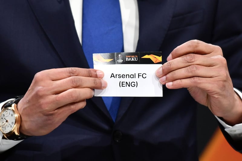 UEFA Europa league ambassador and former Dutch football player Pierre van Hooijdonk  shows the name of Arsenal football club during the draw for the UEFA Europa league quarter-finals draw, on March 15, 2019 in Nyon. / AFP / Fabrice COFFRINI
