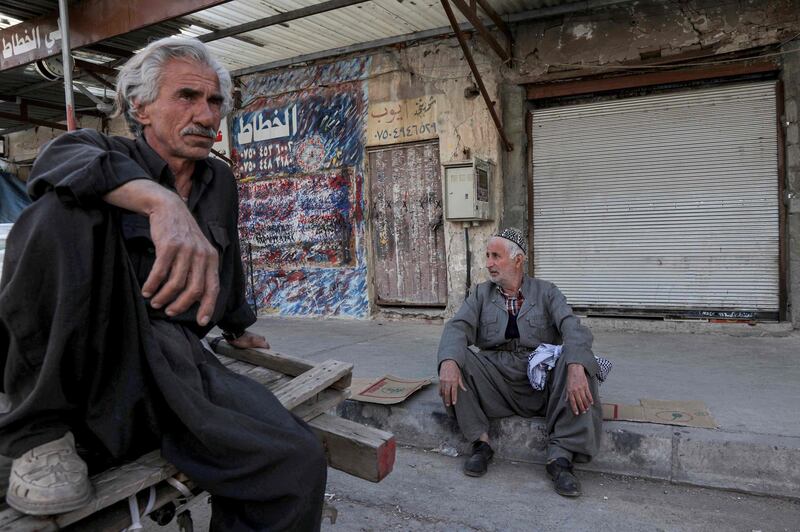 Men sit outside a closed shop along a street in Erbil, the capital of the northern Iraqi Kurdish autonomous region.   AFP