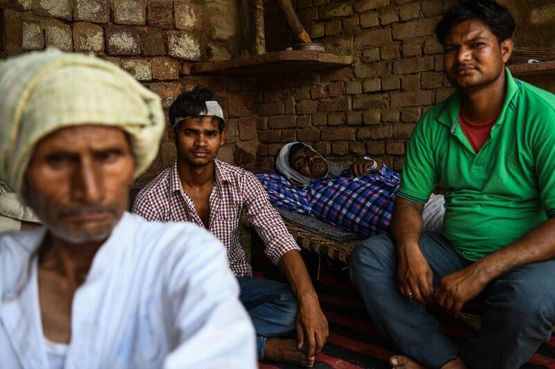 Anil Kumar and Dharamveer Singh sit near the debris of their home which was damaged in the storm. Chandan Khanna / AFP