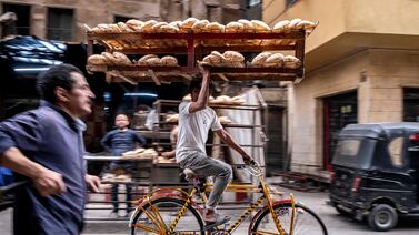 A man balances a tray of freshly baked bread while riding his bicycle in the old quarters of Cairo. AFP