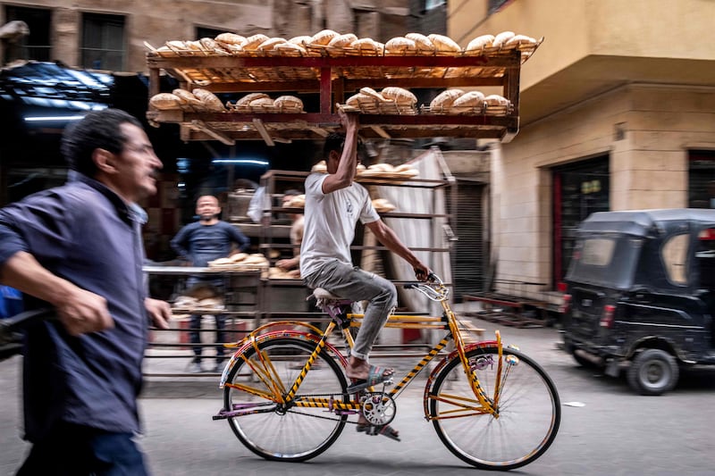 A man cycles in Al-Darb al-Ahmar district in Cairo to deliver a tray of freshly baked bread. AFP