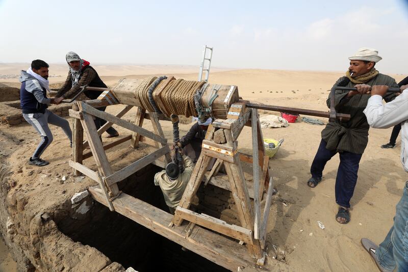 An Egyptian archaeological worker is lowered  inside tombs at Saqqara. EPA