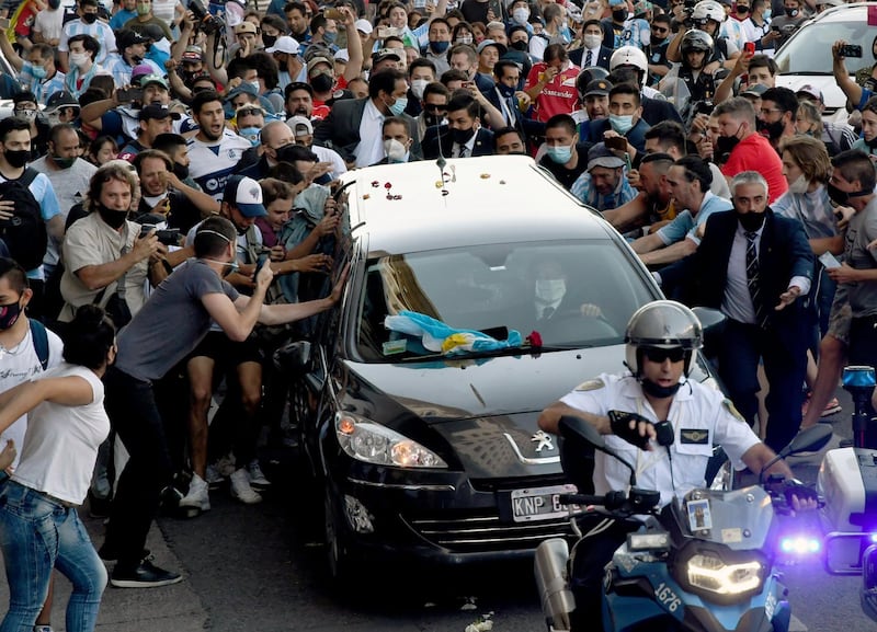 Fans next to the hearse carrying the late Argentine football legend Diego Maradona on its way from Casa Rosada presidential palace to the cemetery, in Buenos Aires. AFP