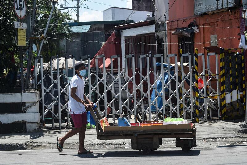 A vendor walks past a neighbourhood under strict quarantine measures in Pasay City, suburban Manila. AFP / Ted ALJIBE