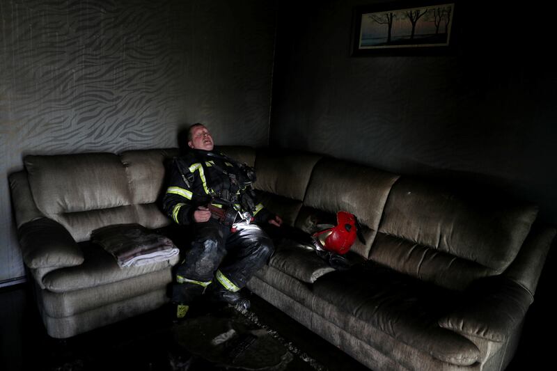 A firefighter takes a break after putting out a fire at a house in a district of Kharkiv that was bombed by Russian forces. Reuters