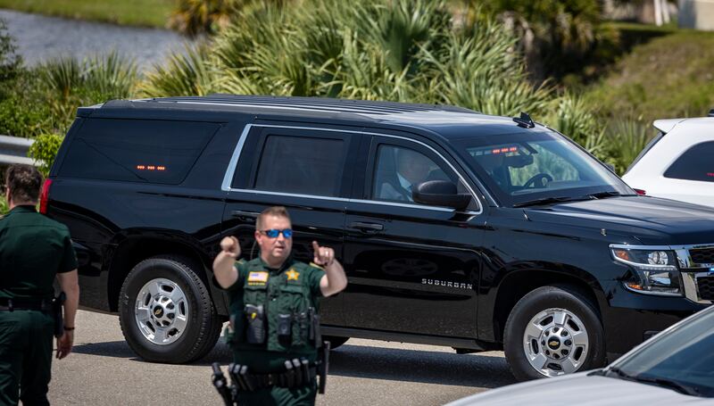 A vehicle in Mr Trump's motorcade heads towards the entrance to the airport past officers directing people to stay away. AP
