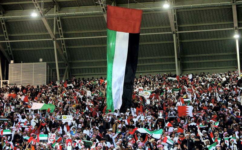 A huge UAE flag hangs over Emarati fans prior the start of the final game between United Arab Emirates and Iraq for the 21st Gulf Cup in Manama, on January 18, 2013. AFP PHOTO/MARWAN NAAMANI
 *** Local Caption ***  288830-01-08.jpg