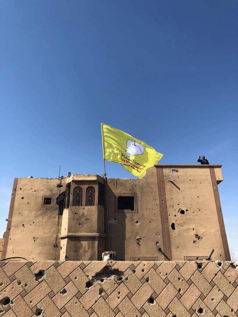 The yellow flag of US-backed Syrian Democratic Forces flies atop a building in the village of Baghouz. EPA