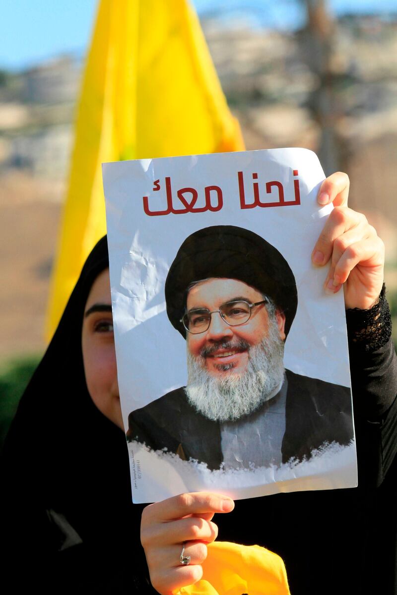 A supporter of Lebanon's militant Shiite movement Hezbollah holds a poster bearing a picture of Hasan Nasrallah during a commemoration marking the 13th anniversary of the end of the 2006 war with Israel in the southern Lebanese town of Bint Jbeil on August 16, 2019. Hezbollah displayed a video showing a sample of its naval missiles, which was used 13 years prior to target an Israeli warship off the Lebanese coast during the July 2006 conflict. / AFP / Mahmoud ZAYYAT
