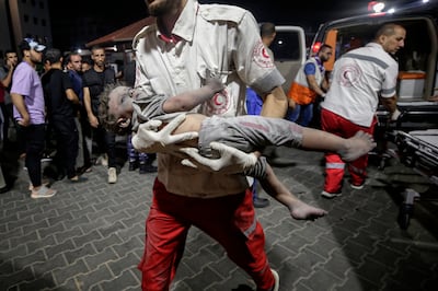 A Palestine Red Crescent Society (PRCS) members carries a wounded child at Al Shifa hospital in Gaza City, on October 9, 2023.  EPA