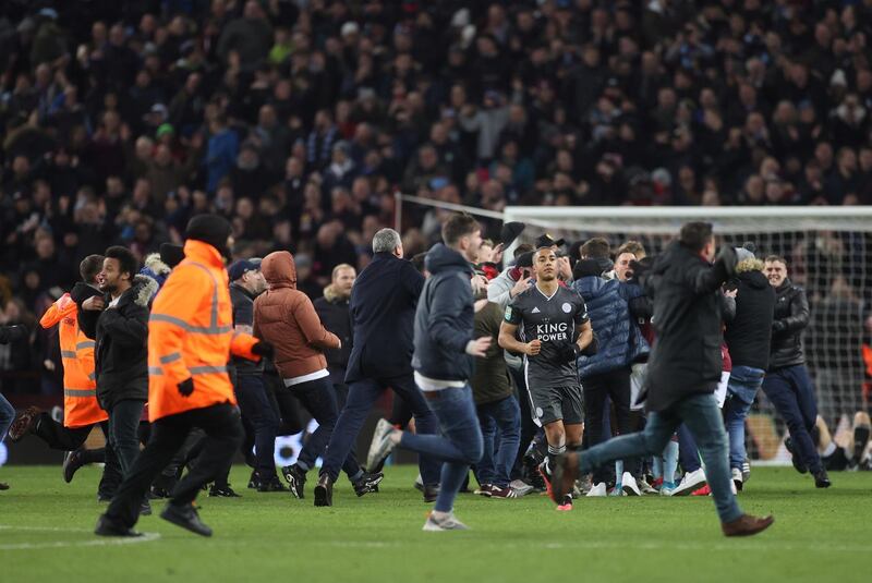 Aston Villa players celebrate with fans on the pitch. Reuters