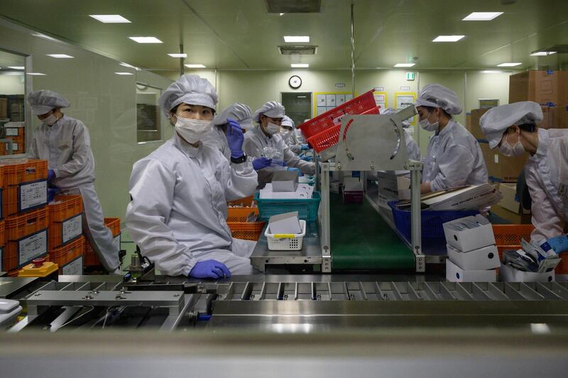 Staff members restock a machine with components used in testing for Covid-19 novel coronavirus. AFP