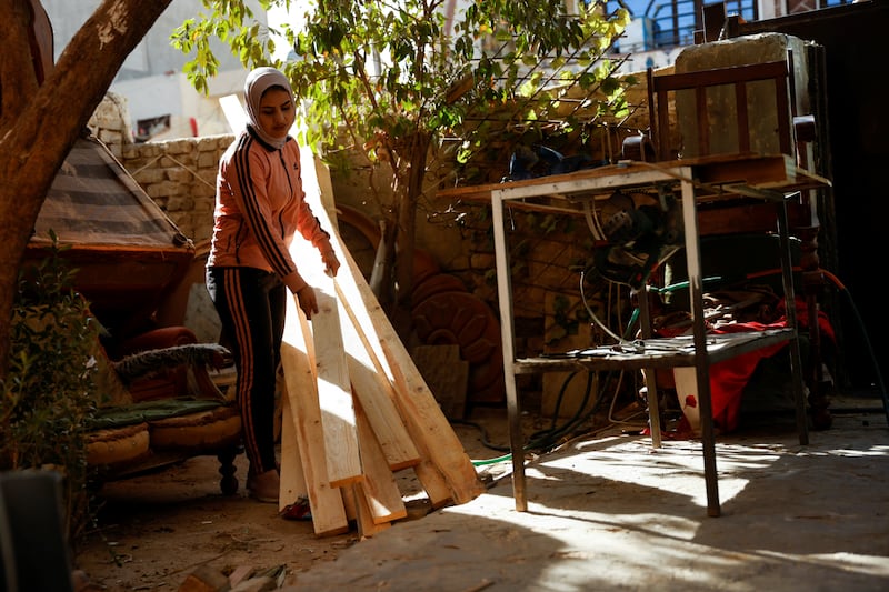 Carpenter Noor Al Janabi carries wooden planks into the garage of her home in Baghdad.