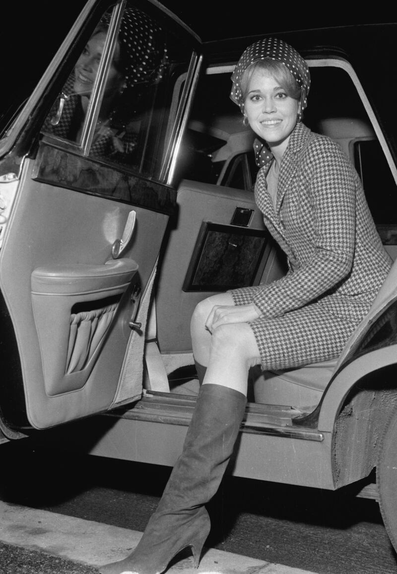 Jane Fonda, in knee-high boots, a houndstooth coat and polka dot headscarf, gets out of her car at London Heathrow Airport on January 23, 1965.