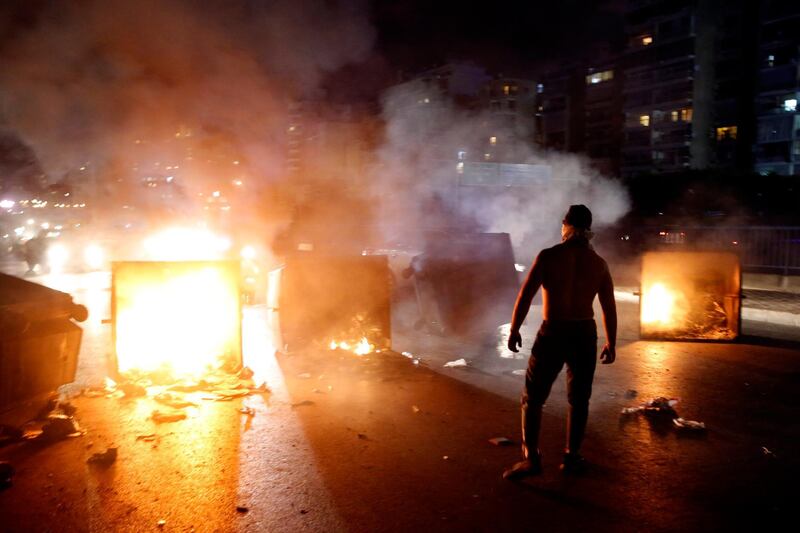 A supporter of Lebanese Prime Minister Saad Hariri burns garbage containers to block  a main road, in Beirut, Lebanon. AP Photo