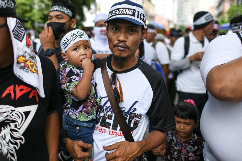 A father carries his son during a rally organised by Muslim politicians against the signing of the UN anti-discrimination convention (ICERD) at Merdeka Square in Kuala Lumpur.  AFP