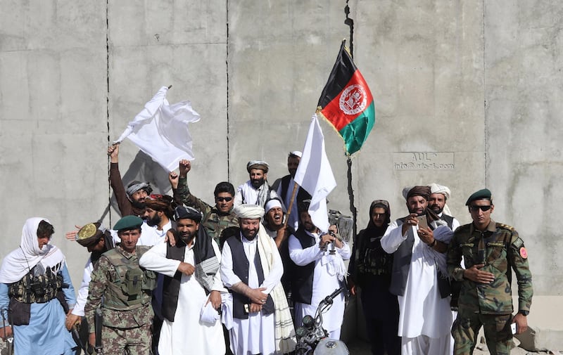 Afghan civilians carrying Afghan national flag along with Taliban flag stand with Taliban fighters and army soldiers to celebrate a three-day ceasefire on the second day of Eid al-Fitr, in the outskirt of Kabul, Afghanistan, on June 16, 2018. Jawad Jalali / EPA
