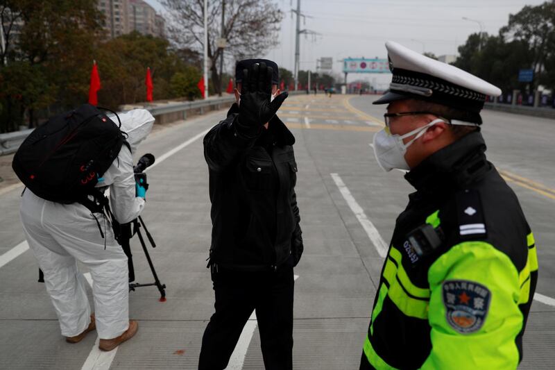 A police officer attempts to prevent the photographer from taking pictures at a checkpoint at the Jiujiang Yangtze River Bridge, as the country is hit by an outbreak of a new coronavirus, in Jiujiang, Jiangxi province, China. Reuters