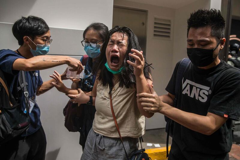 A woman reacts after she was hit with pepper spray deployed by police as they cleared a street with protesters rallying against a new national security law in Hong Kong, on the 23rd anniversary of the city's handover from Britain to China. AFP