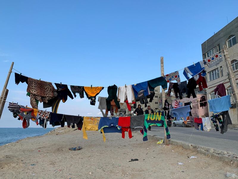 Palestinians walk as laundry hangs on a rope along the beach at Shati refugee camp in Gaza city. Reuters