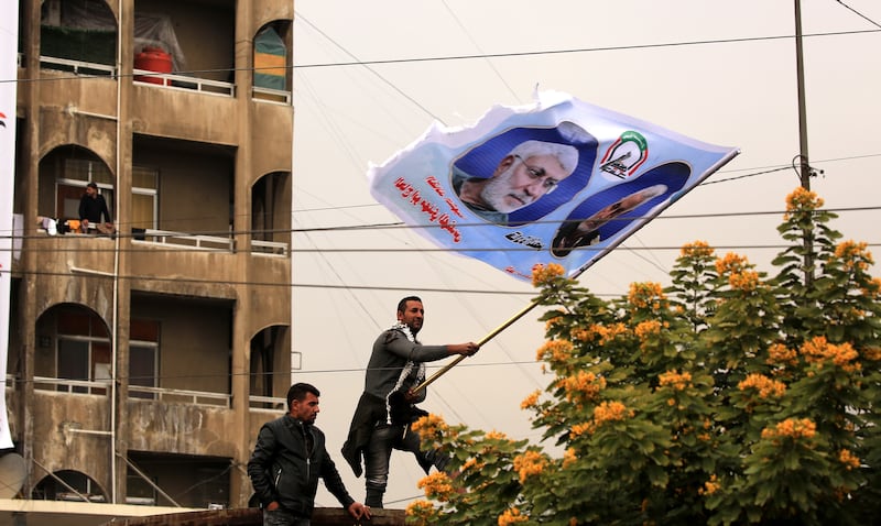 A PMF follower waves a flag depicting Suleimani and Al Muhandis. EPA