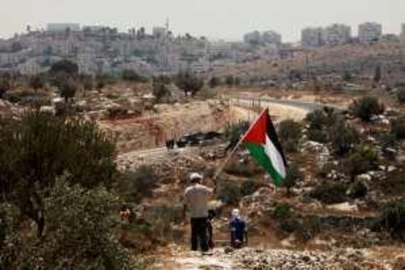 ** CAPTION ADDITION TO ADD CONTEXT OF PROTEST **A demonstrator waves a Palestinian flag on a hill across from Israeli soldiers during a protest at the construction site of Israel's separation barrier in the West Bank village of Nilin, near Ramallah, Wednesday, July 8, 2009. Israel says the barrier is necessary for security while Palestinians call it a land grab. Seen in the background are buildings in the Jwewish settlement of Hashmonaiim. (AP Photo/Tara Todras-Whitehill) *** Local Caption ***  JRL102_ADDITION_MIDEAST_ISRAEL_PALESTINIANS.jpg