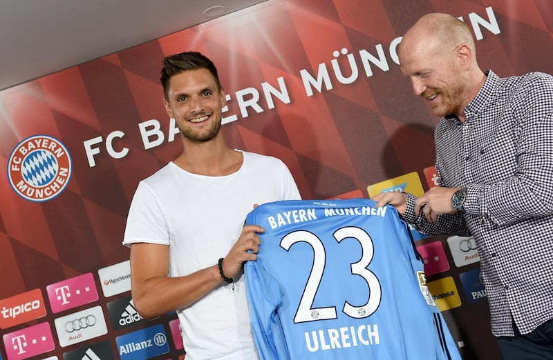 Bayern's director of sport Matthias Sammer (R) hands over a jersey to newly signed goalkeeper Sven Ulreich during a press conference of German First division football club Bayern Munich on July 1, 2015 in Munich, southern Germany. AFP PHOTO / DPA / ANDREAS GEBERT  GERMANY OUT / AFP PHOTO / DPA / MATTHIAS MERZ