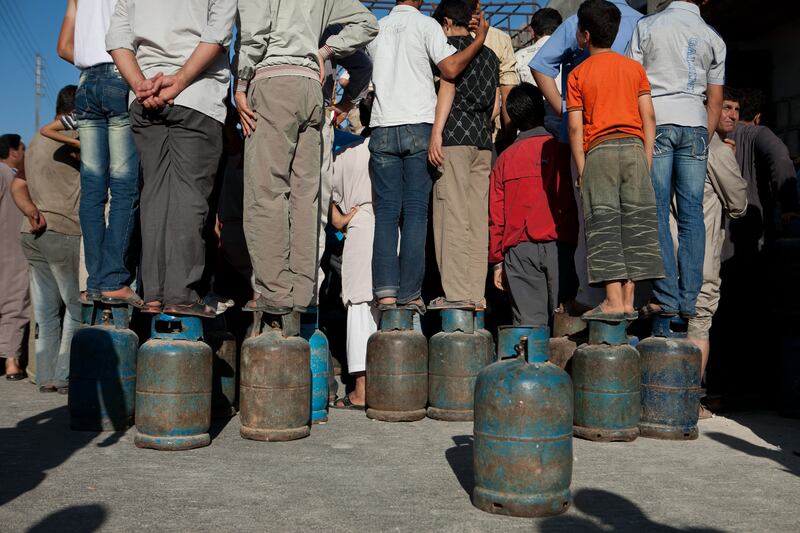 Syrians stand on top of their gas canisters as they wait for a refill in front of a gas lorry provider in Kafranbel, Idlib province. Violence across Syria has resulted in shortages in gas, water and electricity. 