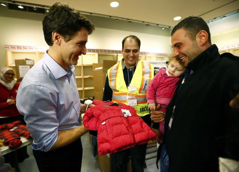 Syrian refugees are presented with a child's winter jacket by Canada's prime minister, Justin Trudeau, (L) on their arrival from Beirut at the Toronto Pearson international airport in Mississauga on December 11, 2015. Mark Blinch/Reuters