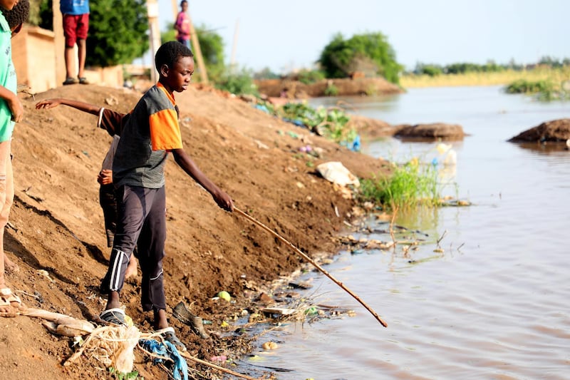 epa08656122 A child fishing in floods water in the Umm Dum area, east of Khartoum, Sudan, 08 September 2020. The Nile’s flooding usually helps farmers in boosting the fertility of their lands, but this year the flooding is so severe that it has caused a dire situation in Sudan, the flood killed at least 100 people, injured dozens and left thousands homeless. Reports add that the floods threaten Sudan’s ancient archeological sites.  EPA/MOHAMMED ABU OBAID