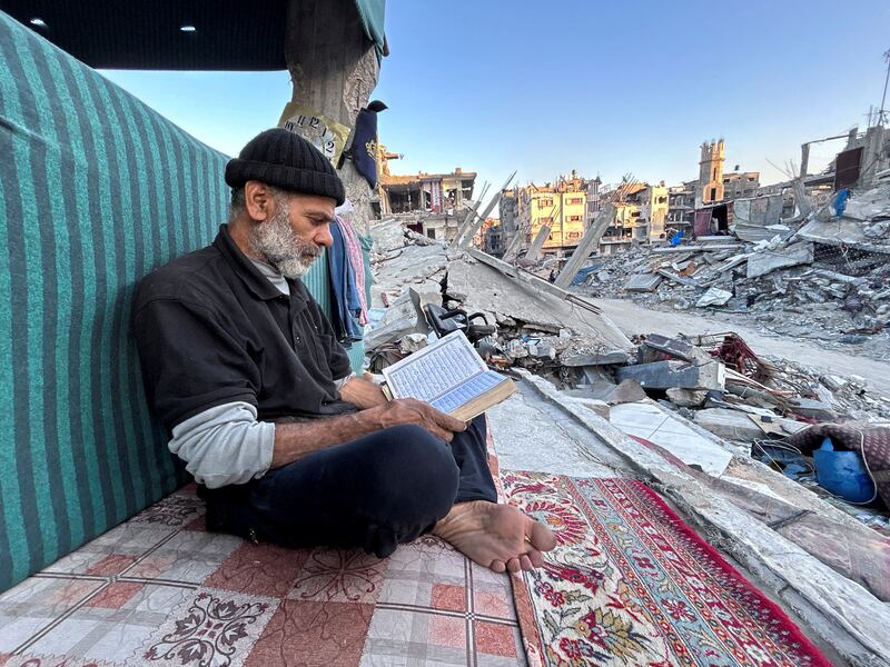 Palestinian man Ismail Al-Khlout reads the Quran as he waits to break his fast while sitting on the rubble of his house, in Beit Lahia, Gaza. Reuters