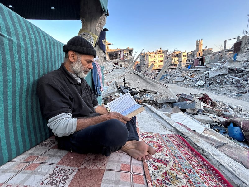 Palestinian man Ismail Al-Khlout reads the Koran as he waits to break his fast while sitting on the rubble of his house, which was destroyed during Israel's military offensive as the conflict between Israel and Hamas continues, during the holy month of Ramadan, in Beit Lahia in the northern Gaza Strip. Reuters