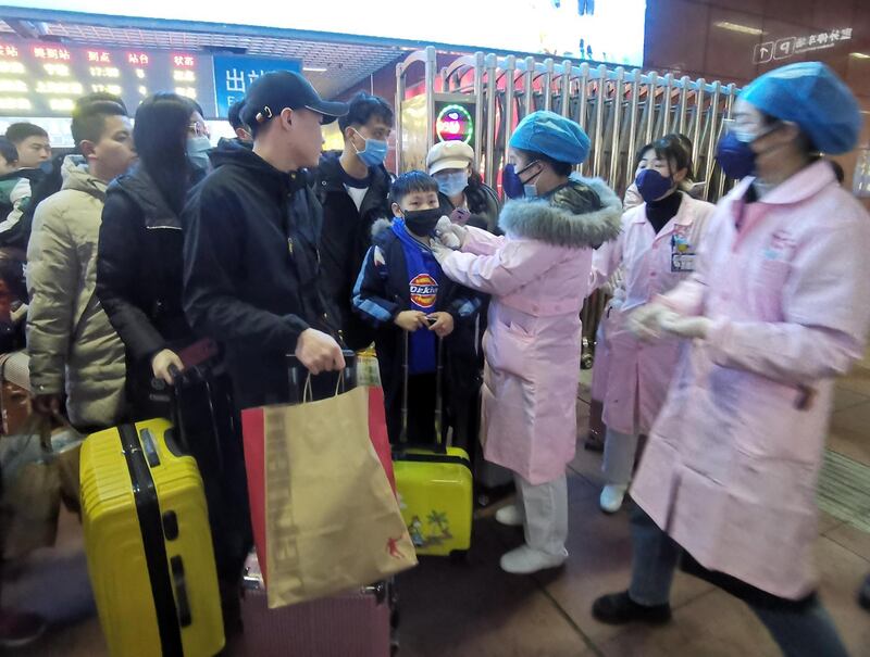 Medical staff check the body temperature of passengers as they arrive at a railway station in Yingtan City, Jiangxi province. EPA