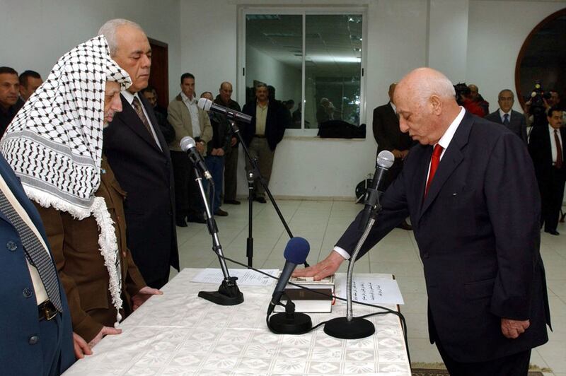 Mr Arafat watches as Mr Qurei swears allegiance on the Quran in November 2003. Getty
