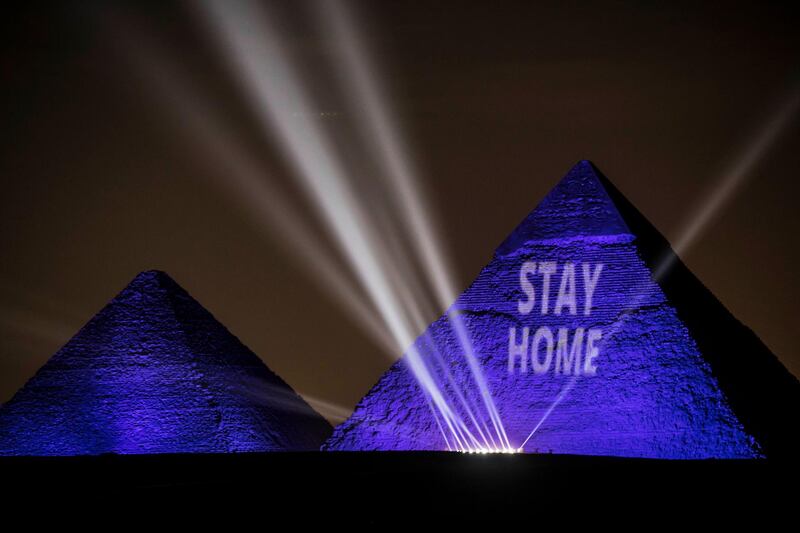 The Great pyramids lit-up with blue light and reading with a laser projection the message "Stay Home" on the Giza plateau outside the Egyptian capital of Cairo on April 18. AFP