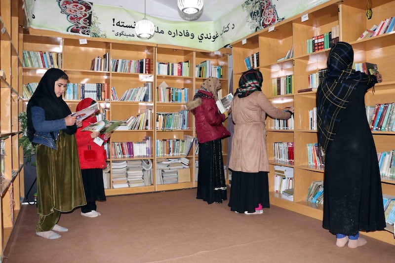 epa09061888 Afghan women read a book at a library, during International Women's Day in Kandahar, Afghanistan, 08 March 2021. International Women's Day is globally observed on 08 March to highlight the struggles of women around the globe. It was proclaimed by the United Nations General Assembly as the day for women's rights and world peace in 1977.  EPA/M SADIQ