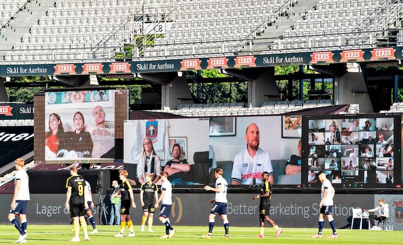 Players are seen on the pitch as fans and players are streamed live on to the screens on the sidelines during the 3F Super League football match between AGF and Randers FC. AFP