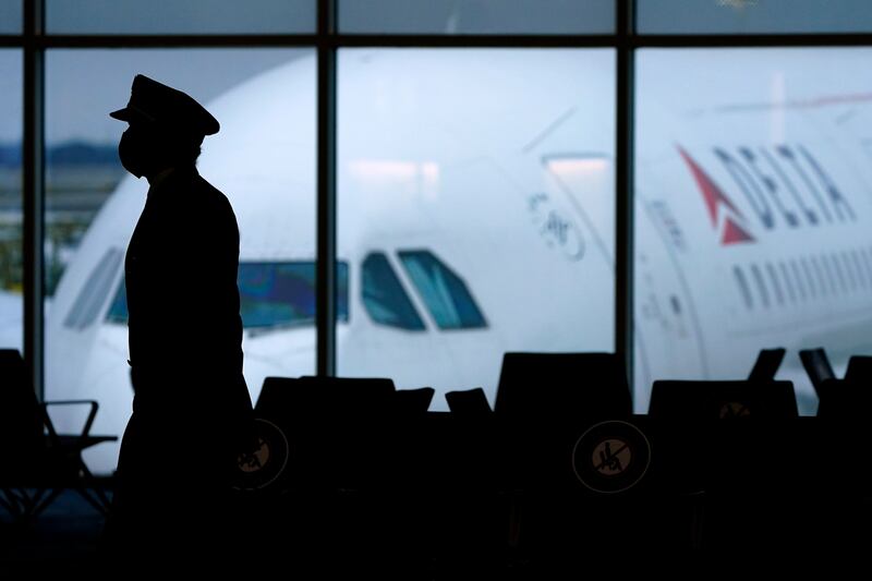 A Delta Airlines pilot wears a face mask as he walks through a terminal at Hartsfield-Jackson International Airport in Atlanta. The aviation industry has experienced a mass departure of skilled workers. AP