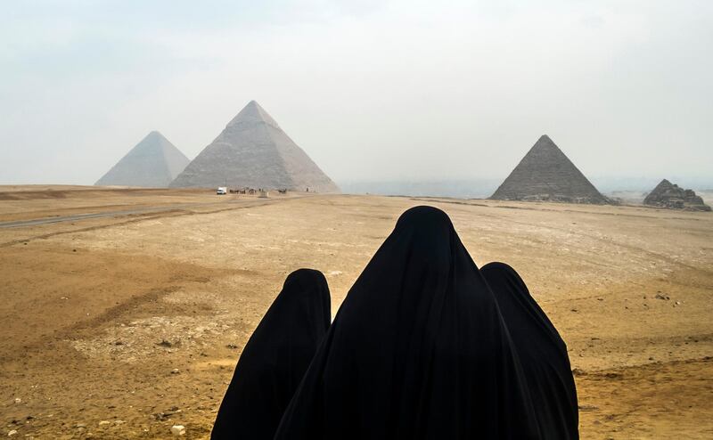 Female tourists wearing veils look at the Pyramids of Giza as they stand from across the Giza plateau, on the southwestern outskirts of the Egyptian capital Cairo on February 15, 2018. (Photo by KHALED DESOUKI / AFP)