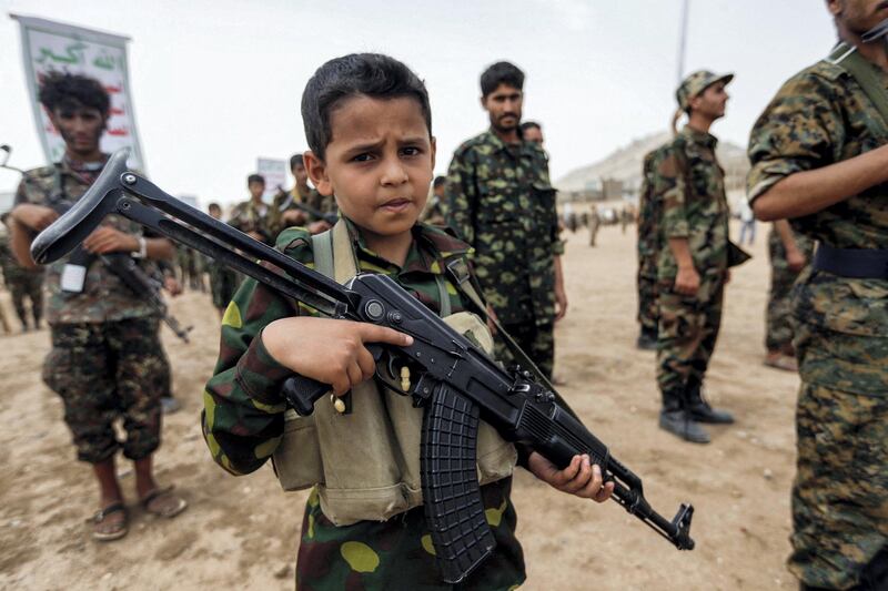 A Yemeni boy poses with a Kalashnikov assault rifle during a gathering of newly-recruited Huthi fighters in the capital Sanaa, to mobilize more fighters to battlefronts in the war against pro-government forces in several Yemeni cities, on July 16, 2017. (Photo by Mohammed HUWAIS / AFP)