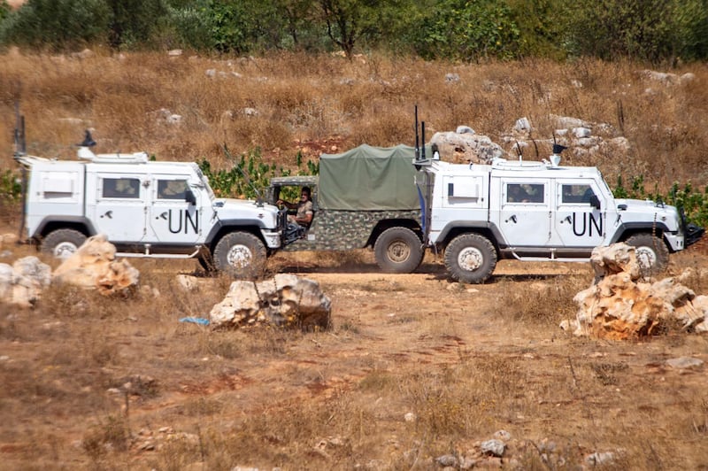 Lebanese soldiers on patrol drive by UN vehicles on the border with Israel on July 28, 2020. AP