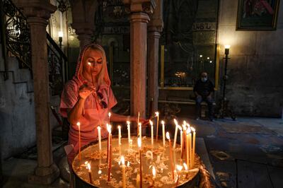 A woman lights a candle at the Church of the Holy Sepulchre in the Old City of Jerusalem. AFP