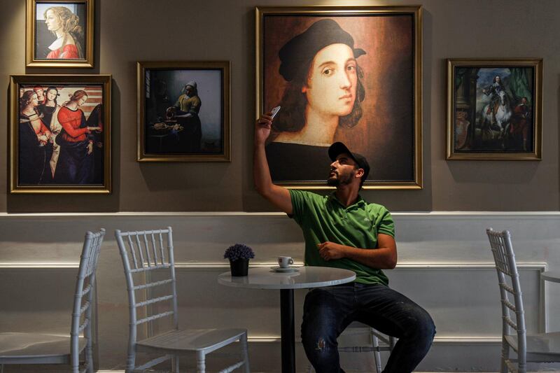 A man holds up his phone as he sits with a cup of coffee at a cafe in Libya's eastern city of Benghazi.  AFP