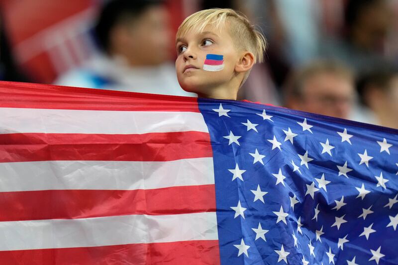 A young fan holds a US flag while waiting for the start of the World Cup match between England and USA. AP