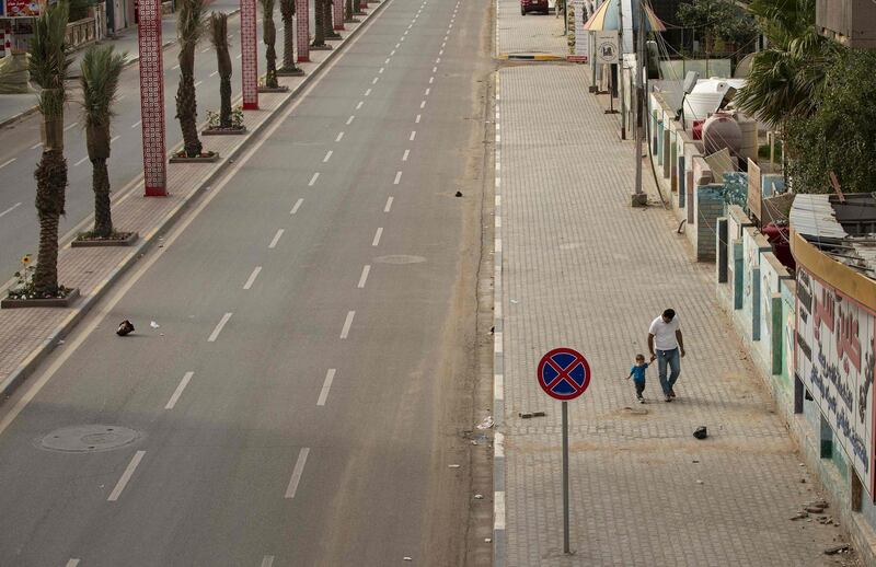 A father walks with his child along a deserted street during a curfew imposed as a measure to stem the spread of the novel coronavirus in Iraq's southern city of Basra. AFP