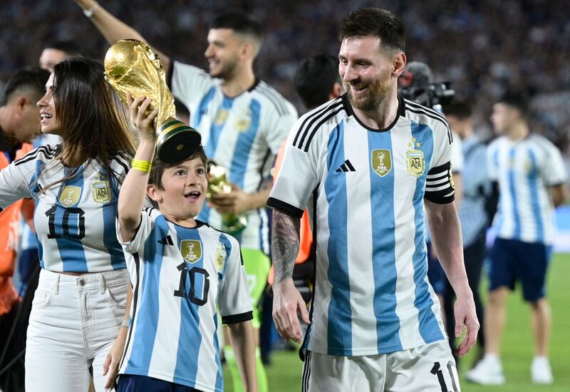 Argentina forward Lionel Messi looks at his son Thiago as he lifts a replica of the World Cup trophy. AFP