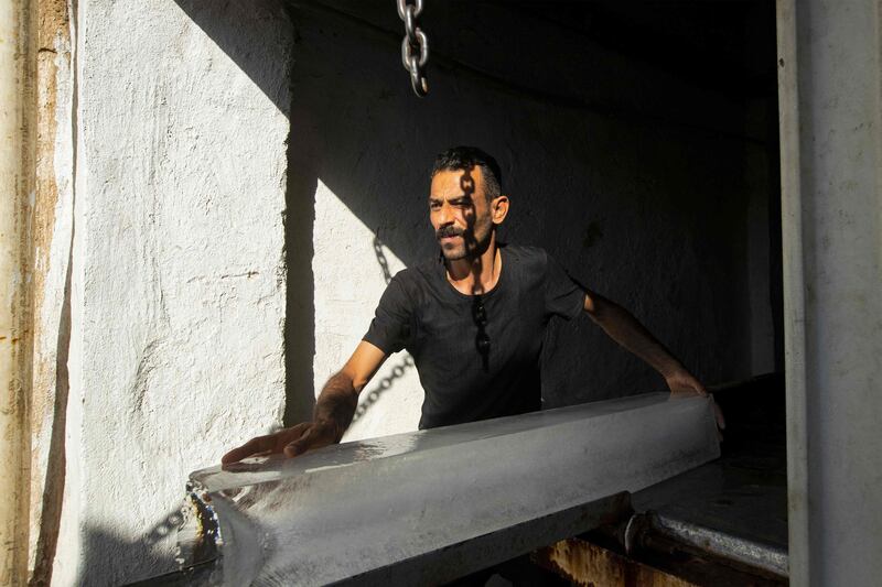 A man takes a block of ice out of an ice factory in Basra. AFP