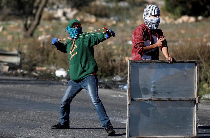 A Palestinian protester uses a sling shot to hurl stones towards Israeli troops near the Jewish settlement of Beit El, near Ramallah. Mohamad Torokman / Reuters