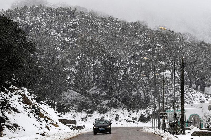 A car drives through falling snow in the city of Ain Draham on the slopes of the Djebel Bir, in Tunisia's northwestern province of Jendouba, about 185 kilometres west of the capital Tunis.   AFP