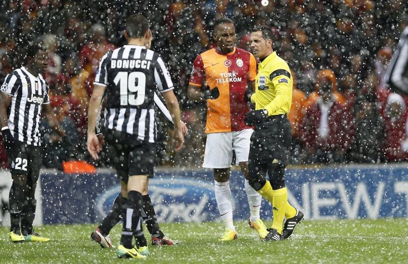 Didier Drogba speaking to referee Pedro Proenca as it snows in Istanbul on Tuesday night. Tolga Bozoglu / EPA